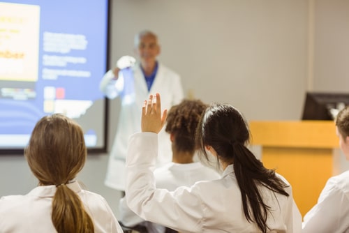 Doctors In Seminar Class With Student Raising Hand